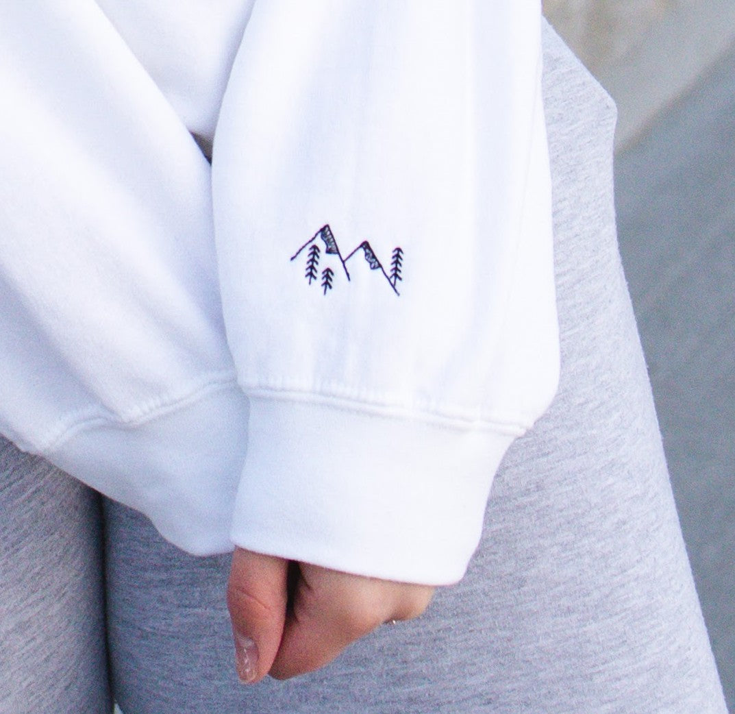 Embroidered mountain and tree sleeve design on crewneck sweatshirt