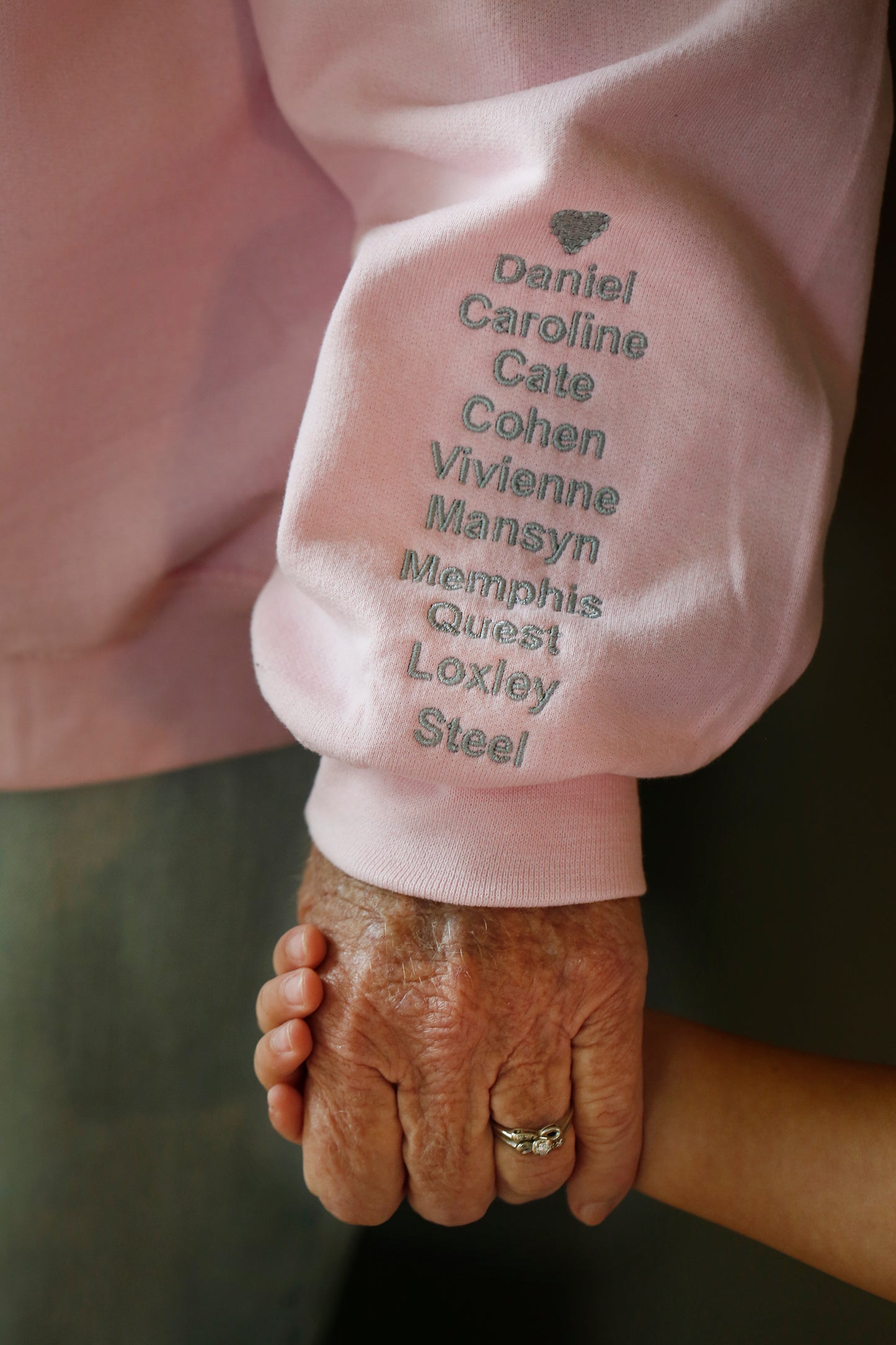 Grandmom collar sweatshirt sleeve with eight kids' names embroidered below a heart