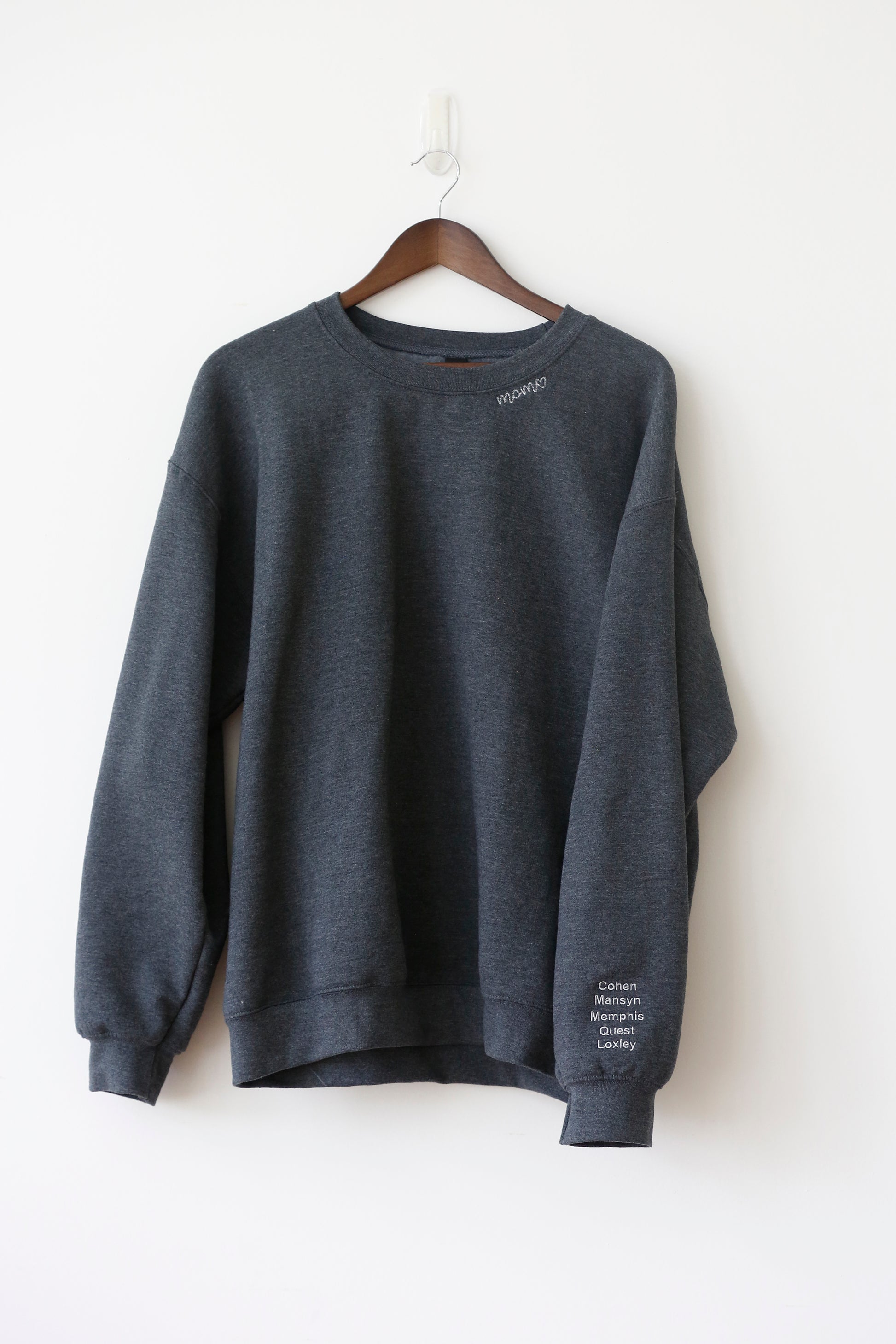 Mama collar sweatshirt with kids' names embroidered on the sleeve, hanging on hanger