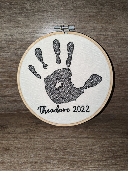 Baby handprint embroidered with name in a 6 inch wooden hoop