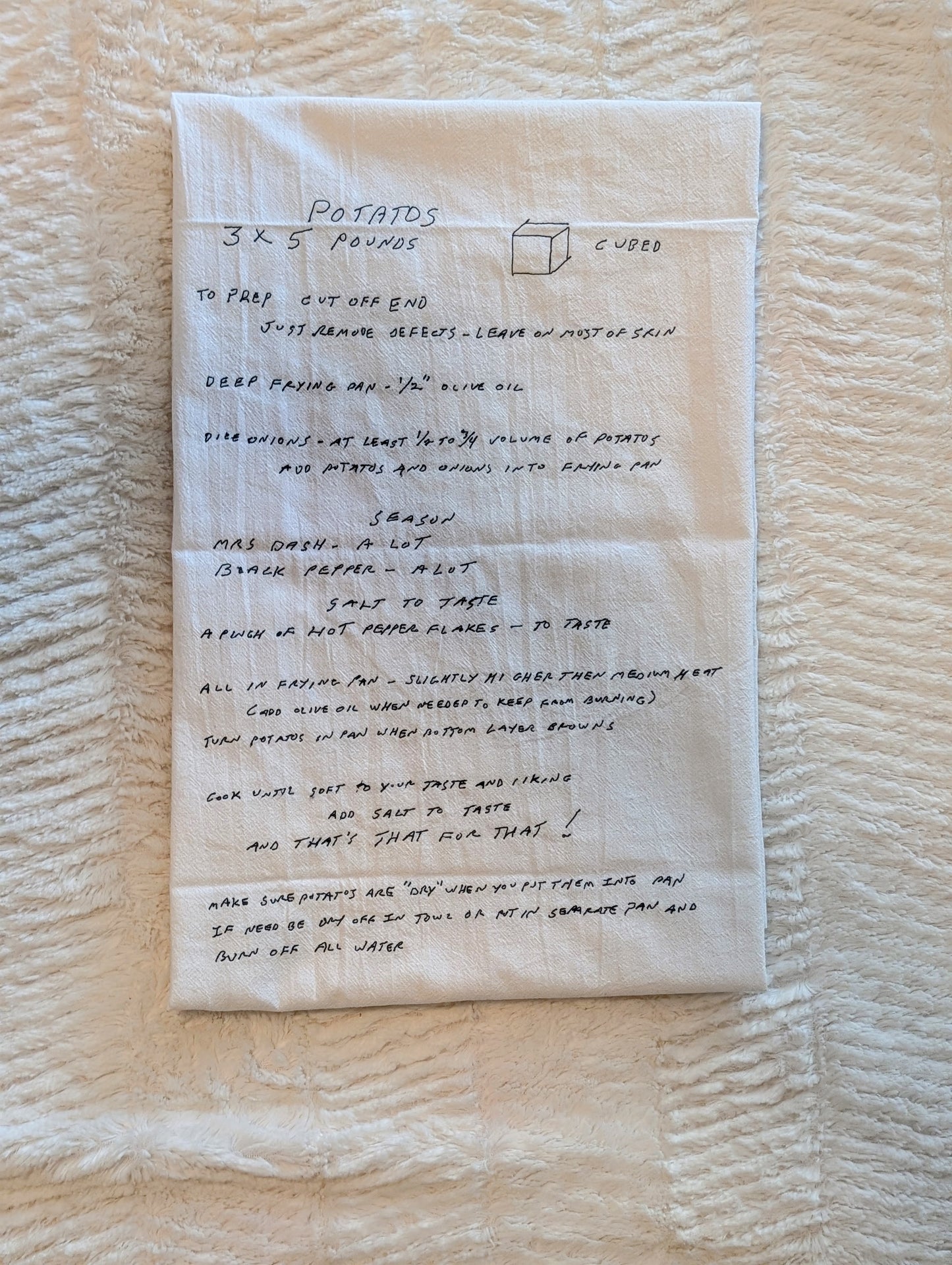 A handwritten recipe card on white paper detailing the preparation of 'Potatoes 3 1/2 POUNDS' with instructions, photographed flat on a textured cream fabric background.